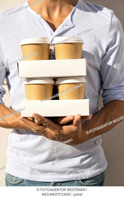 Young man carrying stacks of take away coffee