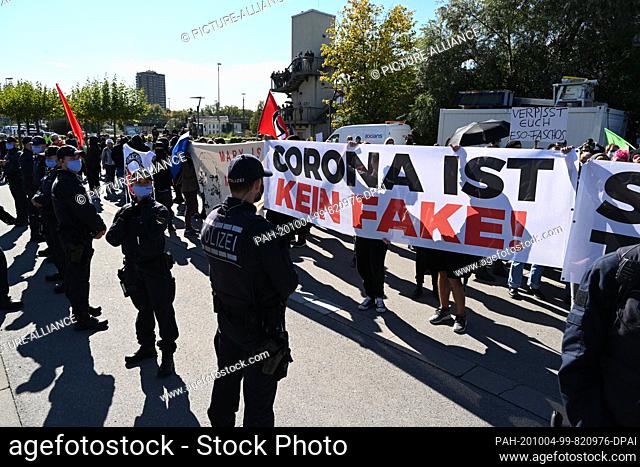 04 October 2020, Baden-Wuerttemberg, Konstanz: Counter-demonstrators hold a banner saying ""Corona is not a fake"" while police officers stop them from meeting...