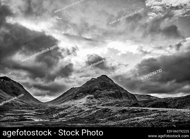Stunning black and white landscape image view down Glencoe Valley in Scottish Highlands with mountain ranges in dramatic Winter lighting