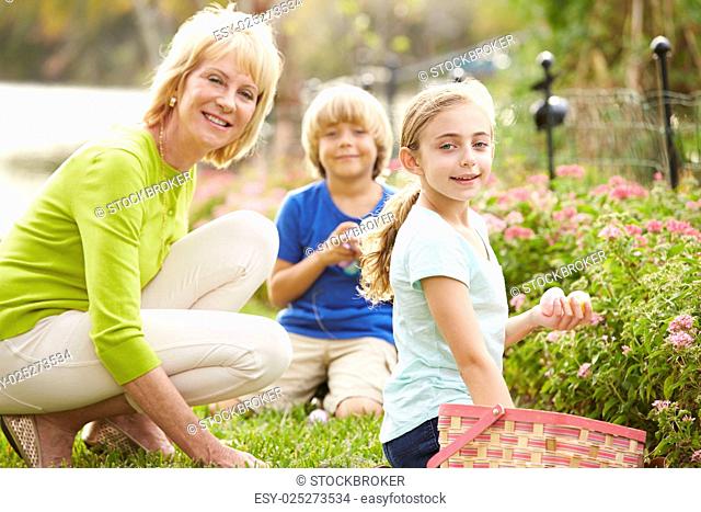 Grandmother With Grandchildren On Easter Egg Hunt In Garden