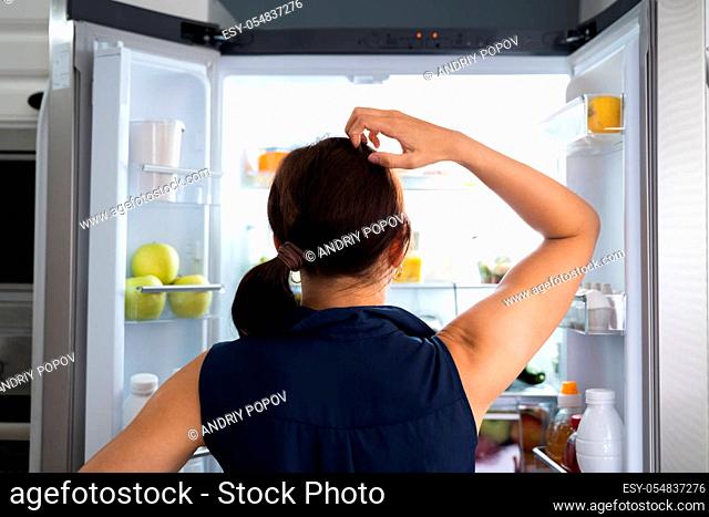 Hungry Women Looking At Food Inside Fridge