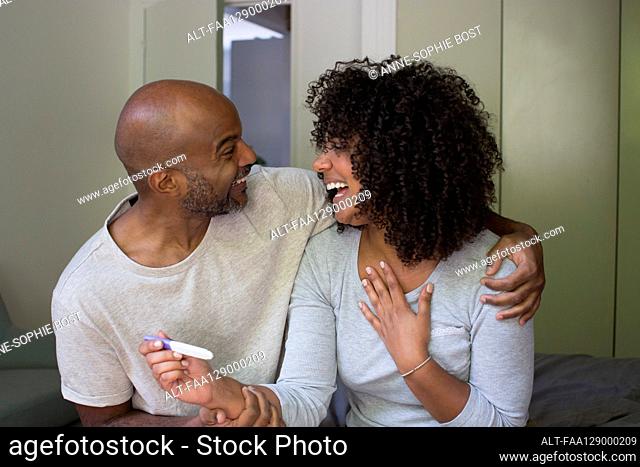 Smiling couple holding pregnancy test kit