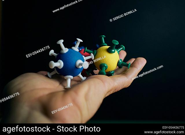 One hand has some models of coronavirus on a black background with copyspace