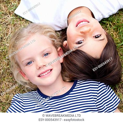 Close-up of cute siblings lying on the grass in a park