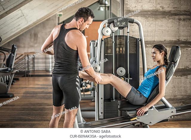 Personal trainer with woman using weight equipment