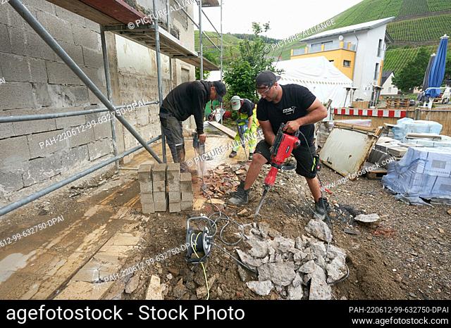 PRODUCTION - 08 June 2022, Rhineland-Palatinate, Dernau: Pompi, (l-r), Anny and Dennis from ""Team Ballern"" are lifting away the remains of the foundation of a...