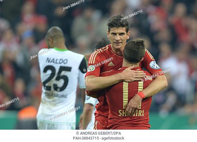 Munich's Mario Gomez (C) embraces team mate Xherdan Shaqiri after the DFB Cup semi-final match between FC Bayern Munich and VfL Wolfsburg at Allianz Arena in...