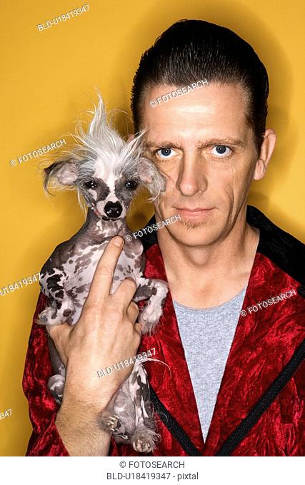 Male wearing velvet and holding Chinese Crested dog