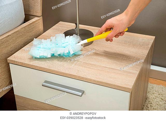 Close-up Of Hand Removing Dust From Nightstand With Duster Feather