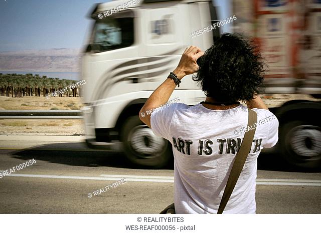 Israel, man taking picture at the roadside while truck is passing by