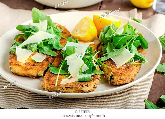 Fried breaded eggplant with salad of arugula topped with parmesan cheese