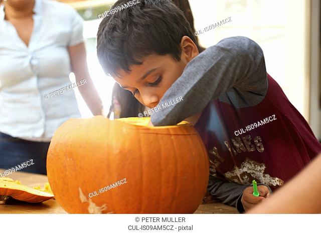 Mother and children hollowing out pumpkin in dining room