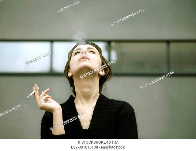 real young woman smokes on the street, selective focus
