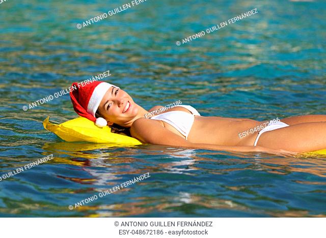 Happy woman enjoying on the beach floating in a transparent tropical water on christmas holiday