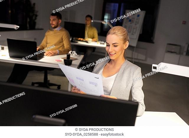 designer working with papers at night office