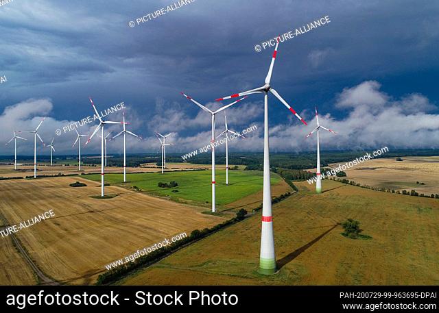 26 July 2020, Brandenburg, Sieversdorf: Dark clouds pass over wind turbines in the ""Odervorland"" wind farm in the Oder-Spree district (aerial photograph taken...