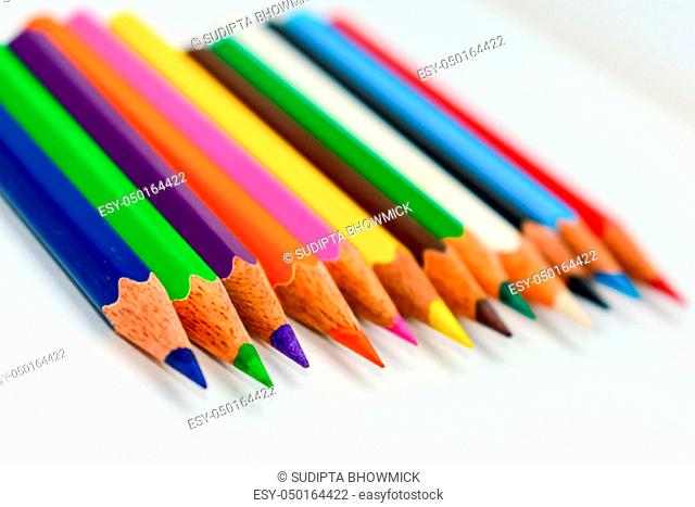 Close-up of a selection of Multi Colored pencils crayons, stick together arranged in a row line bar graph on white background, flat lay