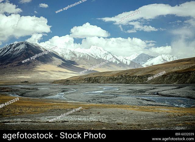 The Wachandarja River meanders through a wide gravel bed on a plateau of the Wakhan Corridor near Bozai Gumbaz, in the background the snow-covered peaks of the...
