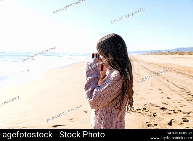 Girl clicking photos from camera at beach