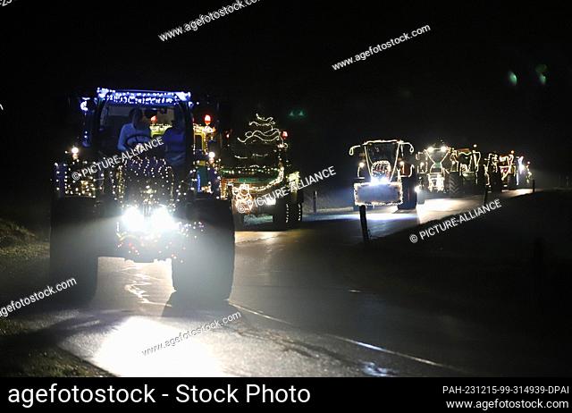 dpatop - 15 December 2023, North Rhine-Westphalia, Kürten: Tractors drive along a road illuminated with fairy lights during a tractor light drive