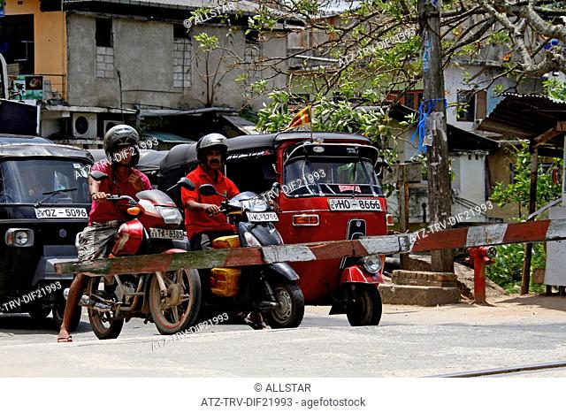 TUC TUCS & MOTORCYCLES AT RAILWAY CROSSING; PERADENIYA, SRI LANKA; 12/03/2013