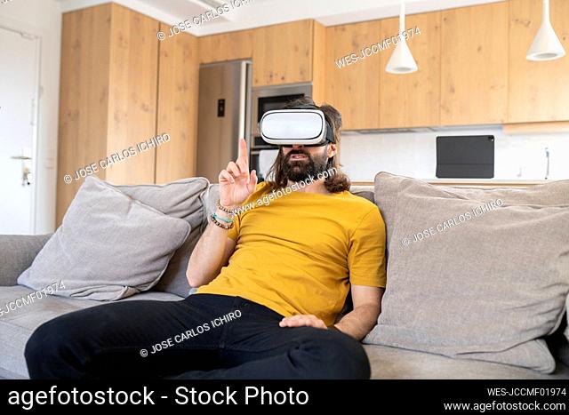 Mature man gesturing while wearing virtual reality headset at home