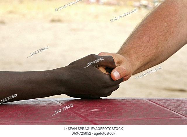 Handshake between a white and a black man. Nyangana, a small village and mission station in the north of the country on the Angolan border