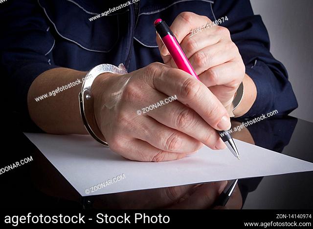 Female hands handcuffed with a pen and a sheet of white paper