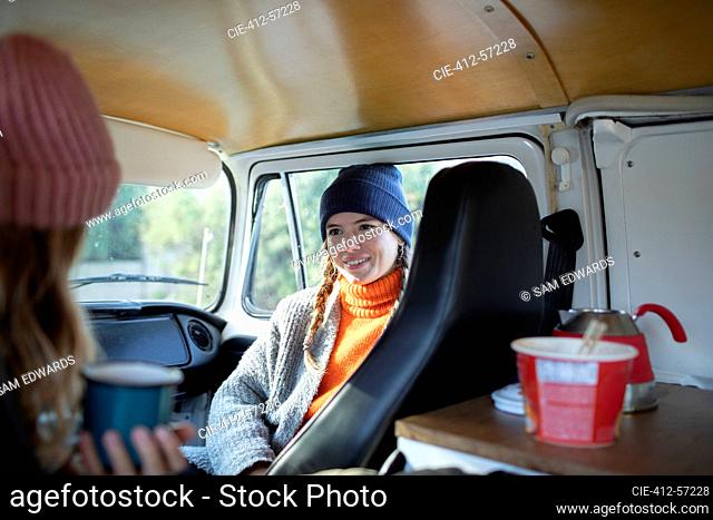 Amigos de las mujeres jóvenes relajándose en autocaravana en viaje por carretera