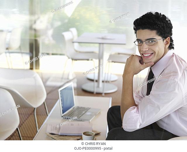 Businessman with laptop and coffee cup smiling