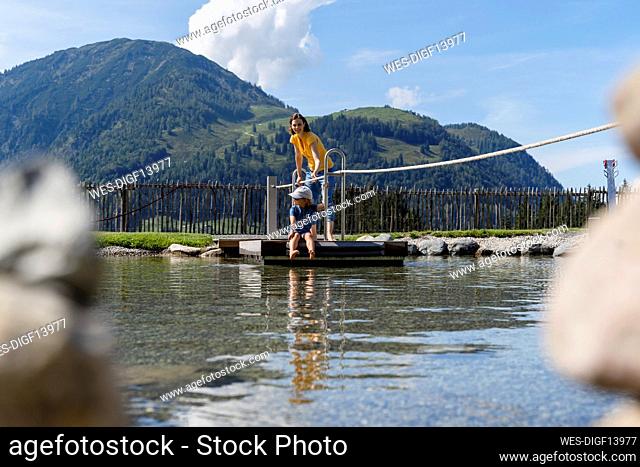 Mother and little daughter crossing lake on small wooden raft