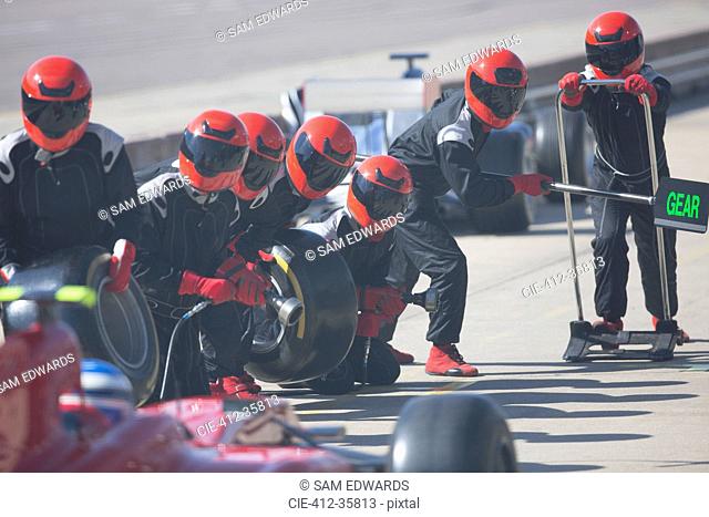 Pit crew with tires ready for nearing formula one race car in pit lane