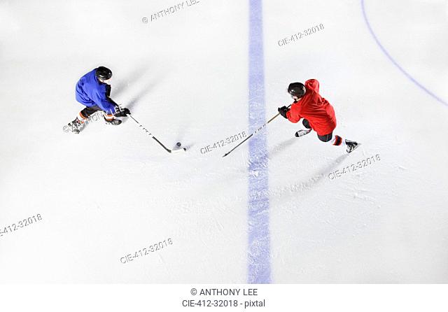 Overhead view hockey players going for puck on ice
