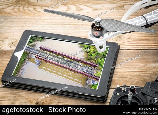 trestle of abandoned railway across a river - reviewing an aerial image on a digital tablet with drone propeller and radio controller