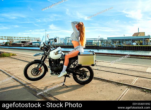 An attractive sexy girl on a motorbike posing outside