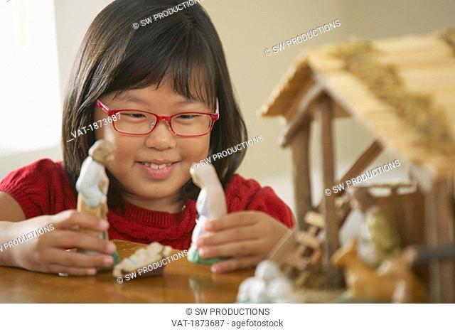 A Girl Plays With The Figurines From A Nativity Scene