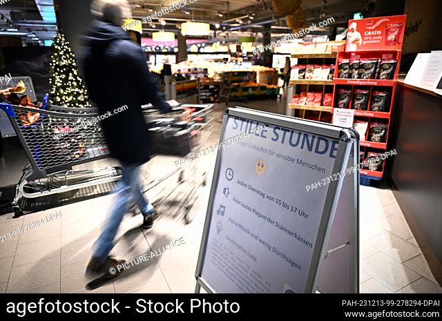 12 December 2023, Baden-Württemberg, Konstanz Am Bodensee: A man pushes his shopping cart into the supermarket, while a sign in the foreground points out the...