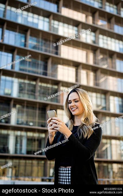 Smiling businesswoman text messaging on mobile phone