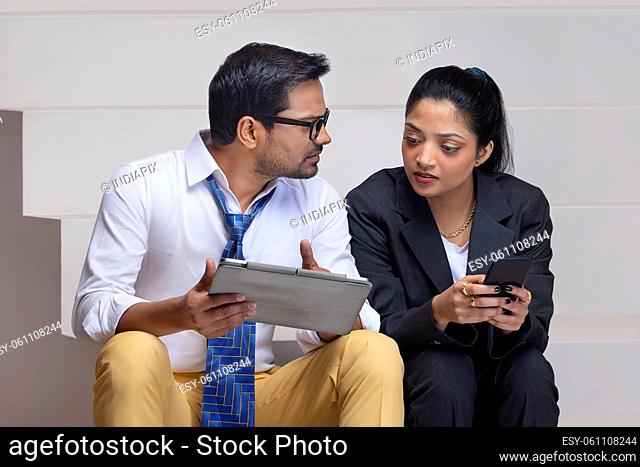 Portrait of a beautiful corporate couple doing office work using digital tablet and smartphone