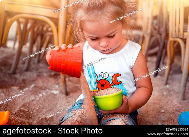 Portrait of a Little Blond Baby Boy Playing with Small Colorful Plastic Sand Toys. Summer Holidays on the Beach. Building a Sandcastle