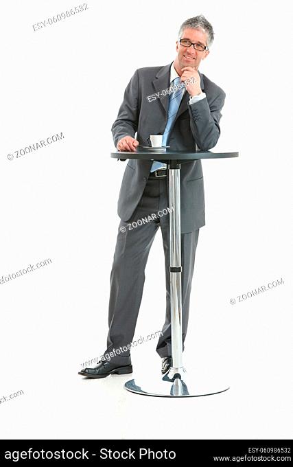 Businessman standing at coffee table, leaning on hand, thinking. Isolated on white