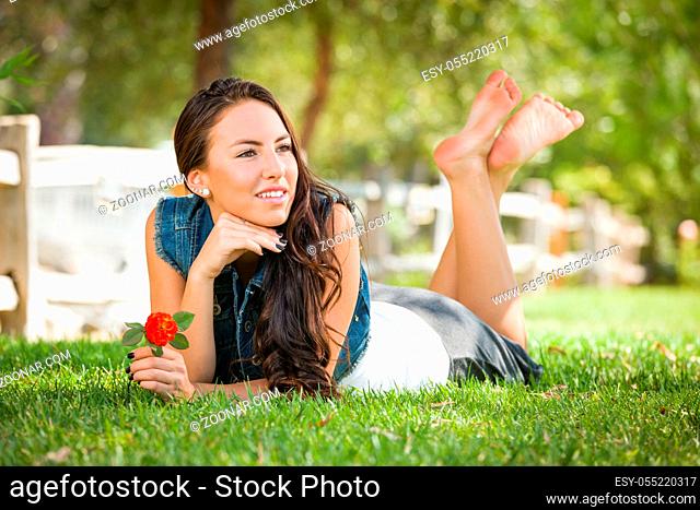 Attractive Mixed Race Girl Portrait Laying in Grass Outdoors with Flower