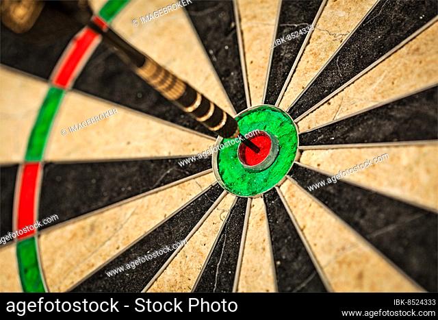 Success hitting target aim goal achievement concept background, dart in bull's eye close up