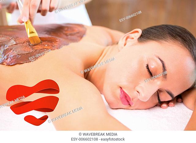 Composite image of attractive woman receiving chocolate back mask at spa center