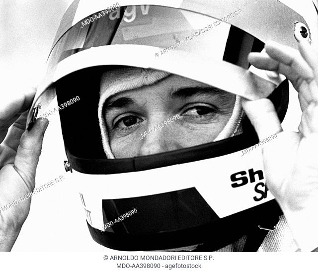Lella Lombardi wearing a full face helmet. Italian racing driver Lella Lombardi (Maria Grazia Lombardi) fixing the visor of her AGV helmet