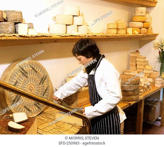 Woman cutting cheese in a cheese shop