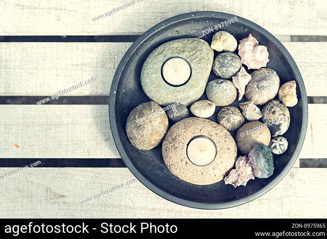 Tealights with pebbles and seashells on a wooden table