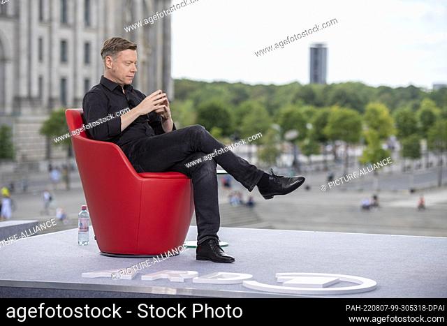 07 August 2022, Berlin: Martin Schirdewan, Co-Vorsitzender der Partei Die Linke, sitzt vor dem ARD-Sommerinterview im «Bericht aus Berlin» auf einem roten...