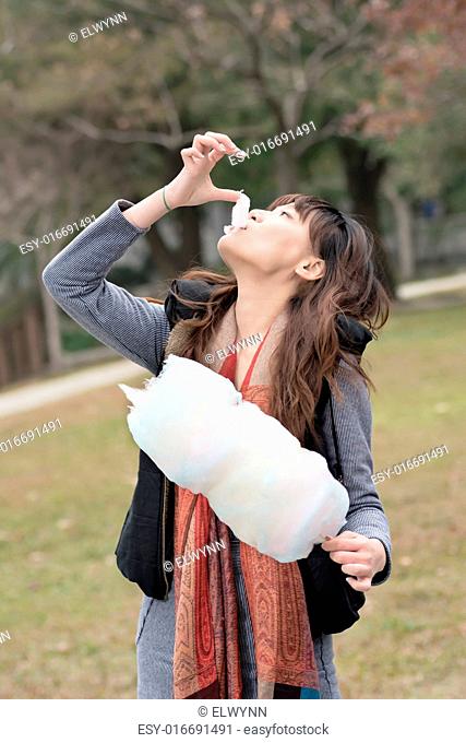 Young Asian woman eating cotton candy in outdoor
