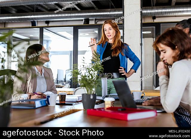 Businesswoman explaining colleagues in meeting at coworking office